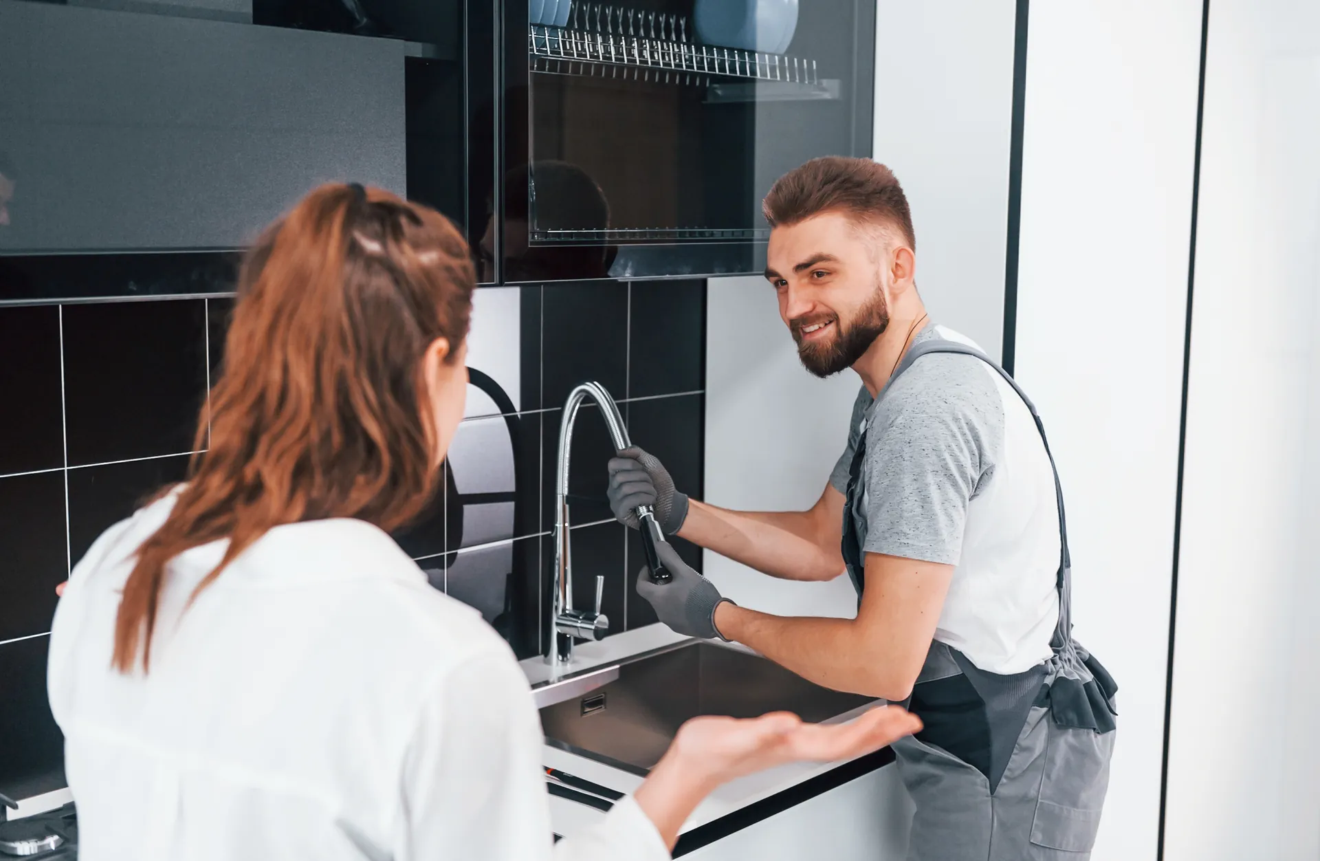 Plumber repairing a kitchen sink faucet for a homeowner